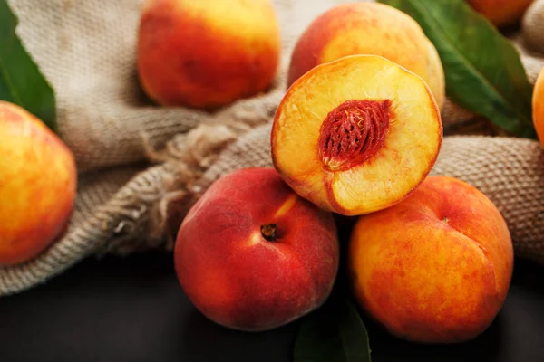 Sweet Peaches on a sharp stone table with a cloth of burlap and a slice of juicy peach with a bone. Top view, free space. Country style