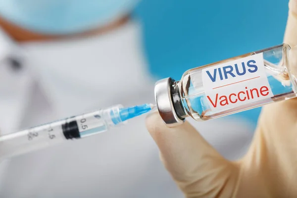 An ampoule with the inscription Virus Vaccine and a syringe in the hands of a scientist doctor in rubber gloves with a vaccine close-up. Medicine for flu, measles, coronavirus, covid-19 vaccine disease, pandemics