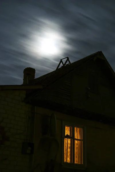 Casa con una finestra luminosa sullo sfondo di una nuvola, luna Immagine Stock