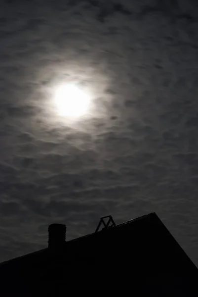 Notte al chiaro di luna con nuvole galleggianti sopra la casa del villaggio . Foto Stock