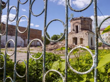 Bir metal çit arkasında harap durumda Tuğla eski altıgen bina.