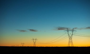 Elektrik hatları alacakaranlıkta aydınlanıyor.