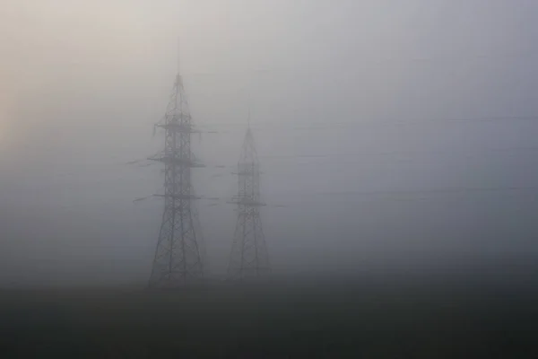 Ondersteuning van hoogspanningsleidingen in mist — Stockfoto