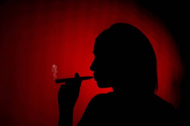 Silhouette of a female smoking an ecig on a red background clipart