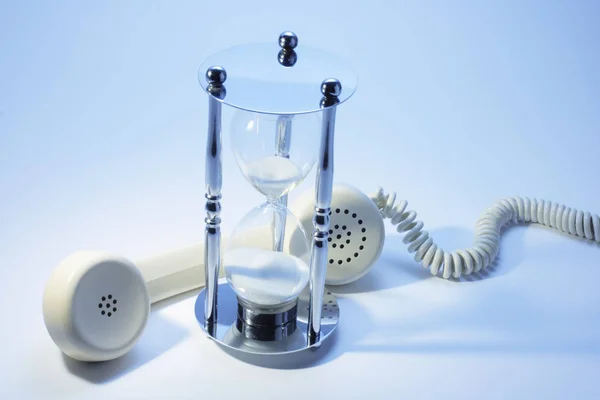 電話の受話器と青色の背景色の砂時計 — ストック写真