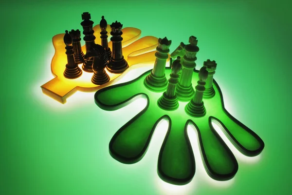 背景が緑色のプラスチックの手にチェスの駒 ストック写真