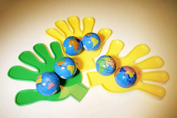 Plastikhände Mit Globen Auf Warmem Hintergrund — Stockfoto