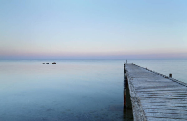 Wooden jetty in a tranquil seashore while sun is getting set at Brondbystrand, Denmark