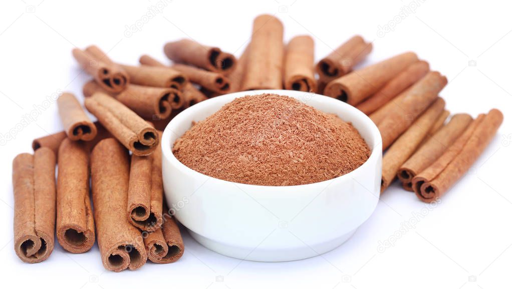 Bunch of some fresh aromatic cinnamon with powder spice over white background