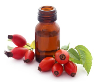Beyaz arka plan üzerinde cam şişede uçucu yağ ile tıbbi Rose HIPS