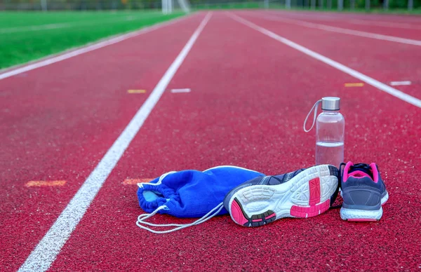 Shoes and other items on athletic track at afternoon