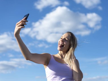 Genç bir kadın akıllı telefonuyla selfie çekiyor.