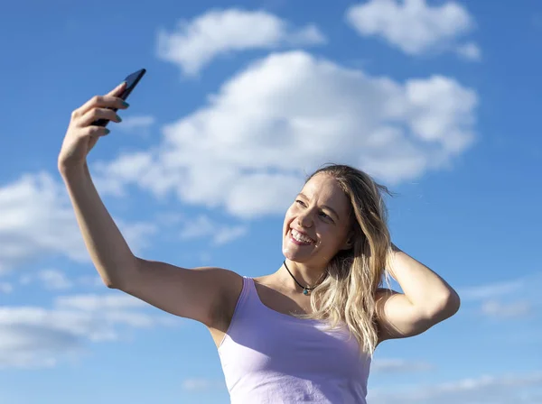 若い女性がスマホで自撮りして — ストック写真