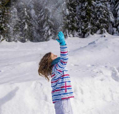 Mutlu genç kız karla oynuyor.  