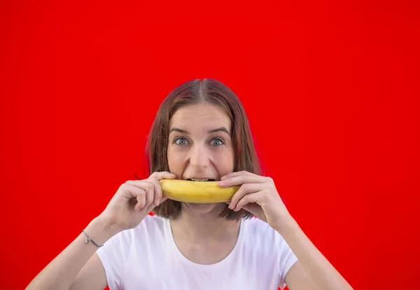 Feliz Chica Joven Con Plátano Sobre Fondo Rojo Imagen de stock