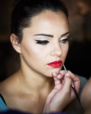 Makyöz, genç bir kadının profesyonel makyajını yapıyor. Güzellik serin.