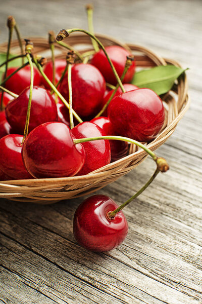 Fresh red cherries in basket on wooden table