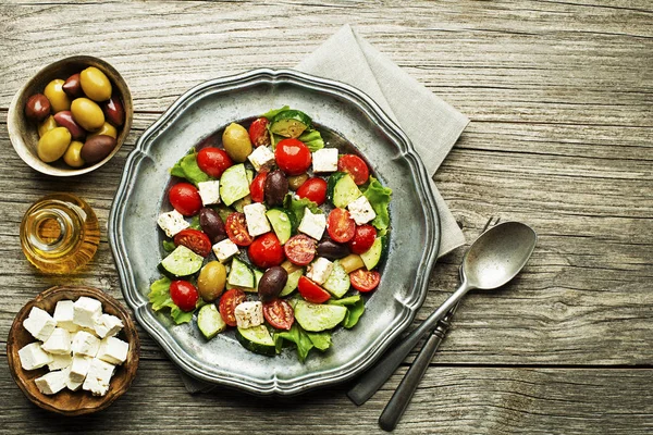 Beyaz peynirli salata ve ahşap arka planda taze sebzeler. Yunan salatası.