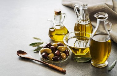 Şişe ekstra sızma sağlıklı zeytinyağı gri arka plan üzerinde taze zeytin ile