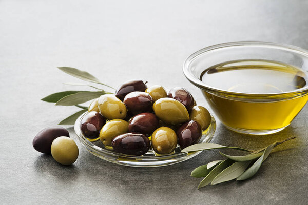Olive oil in glass bowl with fresh olives fruit