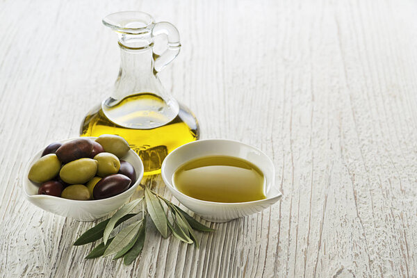 Bottle of Extra virgin healthy Olive oil with fresh olives on wooden background