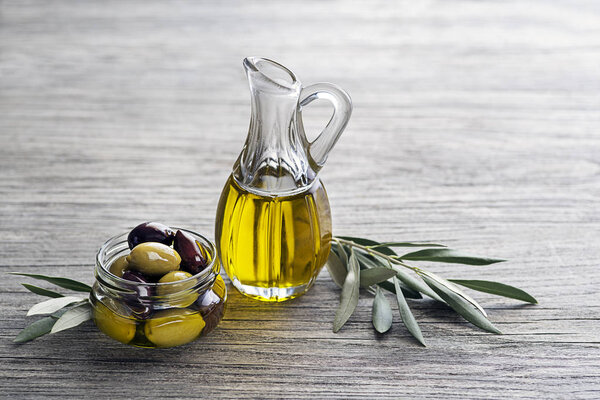Bottle of Extra virgin healthy Olive oil with fresh olives on wooden background