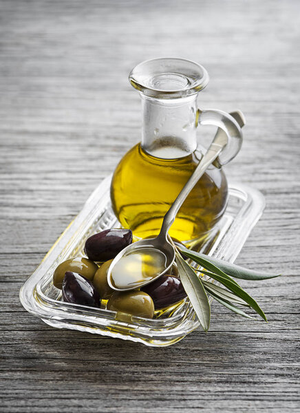 Bottle of Extra virgin healthy Olive oil with fresh olives and spoon close up