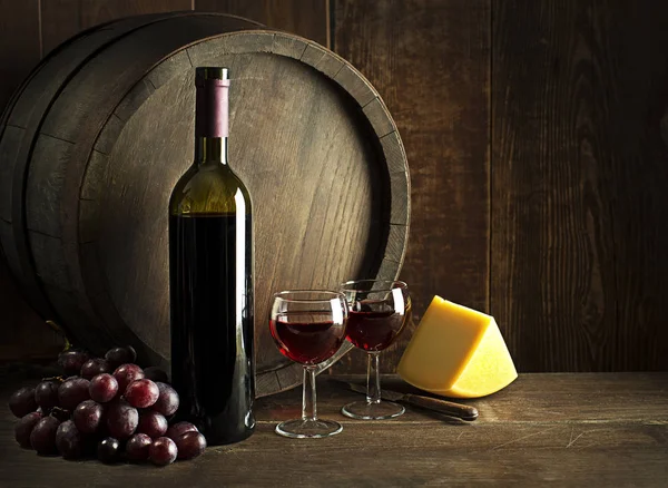 Bir Şişe Kırmızı Şarap Bardaklar Peynirler Ahşap Fıçı Arka Planda — Stok fotoğraf