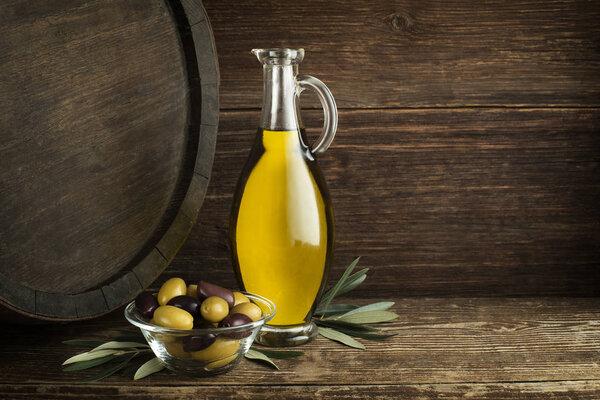 Bottle of Extra virgin healthy Olive oil with barrel background