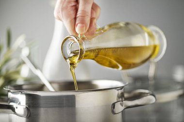 Bir tencerede yemek. Ekstra şişe saf yağı yemek pişirme için pota yağıyor. Sağlıklı gıda kavramı. 
