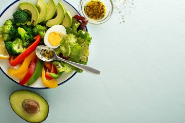Yumurtalı sağlıklı salata menüsü, avokado ve mavi arka planda taze sebzeler. Sağlıklı yemek kavramı