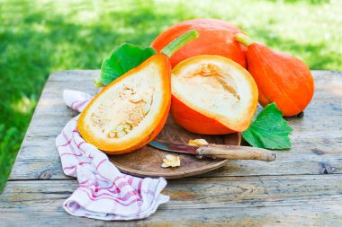 Hokkaido balkabağı kesmek ya da kırmızı kuri kabağını bıçakla yakın plan kesmek. Dışarıda, bahçede.