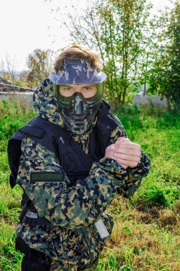 Eğitim sahasında piksel kamuflaj üniforması giyen, maske takan ve gözlük takan bir asker.