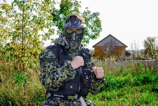 military recruit in a pixel camouflage uniform, wearing a mask and goggles during training at the training ground