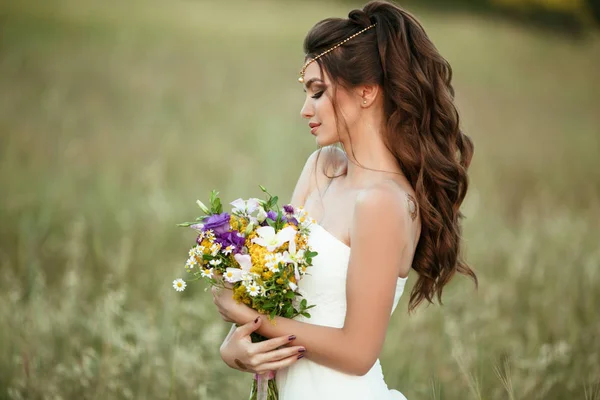 Beautiful young bride is wearing teak with fashion bouquet of wildflowers in yellow field, nature wedding concept — Stock Photo, Image