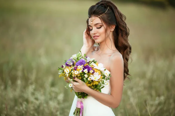 Mooie jonge bruid is het dragen van teak met mode boeket van wilde bloemen in geel veld, natuur bruiloft concept — Stockfoto