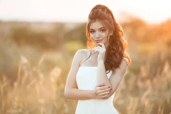 Portrait of beautiful happy young bride in field over sunset lights — Stock Photo, Image