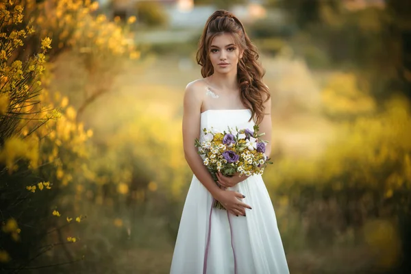 Beautiful young bride with fashion bouquet of wildflowers in yellow field, nature wedding concept — Stock Photo, Image