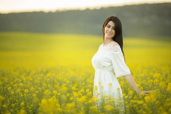 Mutlu genç kadın günbatımı ışıklar, yaz saati sarı alanında kır çiçekleri buketi ile