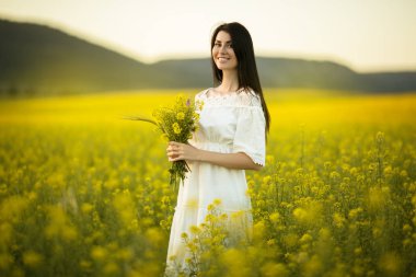 Güzel gün batımı ışıklar, yaz saati sarı alanında kır çiçekleri buketi kadınla