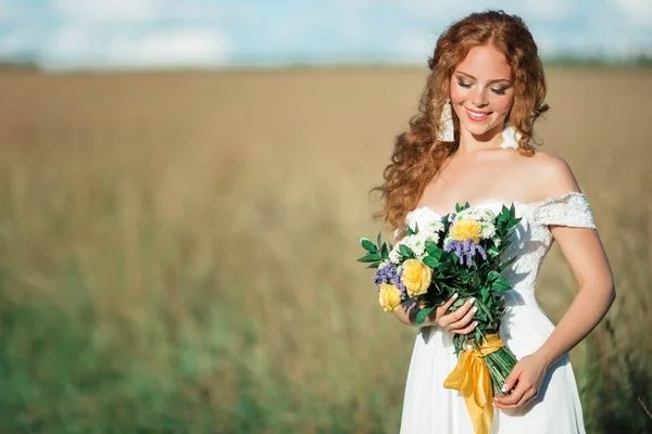 Bonita novia pelirroja en el campo con ramo de flores silvestres —  Fotos de Stock