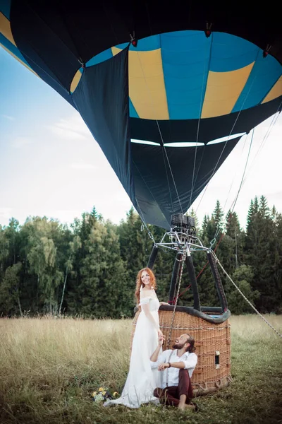 Casal feliz casamento está se divertindo perto de airballoon no campo ensolarado . — Fotografia de Stock