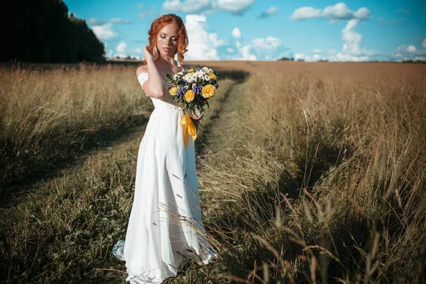 Bonita novia en el campo con ramo de flores silvestres — Foto de Stock