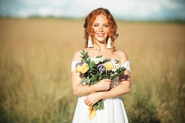 Retrato de novia bonita con pecas en su cara en el campo con ramo de flores silvestres —  Fotos de Stock