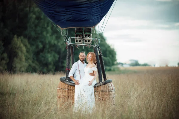 Casal feliz do casamento está sentado dentro da cesta do airballoon no campo ensolarado . — Fotografia de Stock