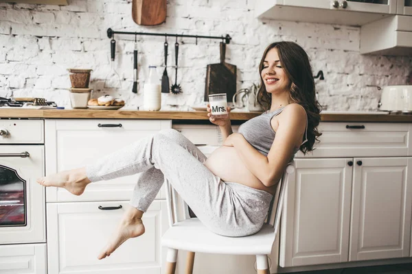Hermosa mujer embarazada en la cocina con taza de leche — Foto de Stock