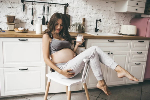 Hermosa mujer embarazada en la cocina con taza de leche — Foto de Stock