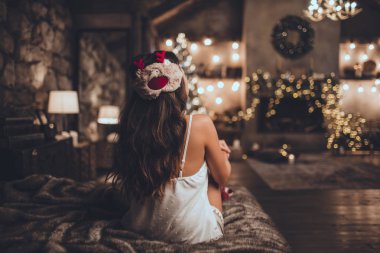 Güzel Asyalı kadın yatakta yatan ve Noel ağacı yakınındaki uyku maskesi evde rahat iç giyiyor. Noel süslemeleri ile iç.