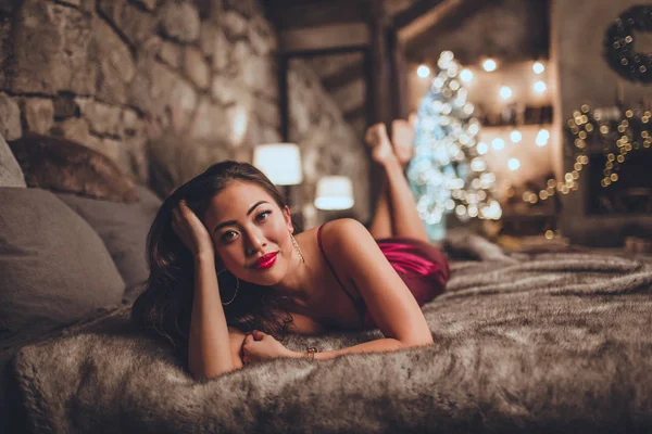 아름 다운 아시아 여자는 아늑한 인테리어에 크리스마스 트리 근처 집에서 앉아 있다. 크리스마스 장식 인테리어. — 스톡 사진