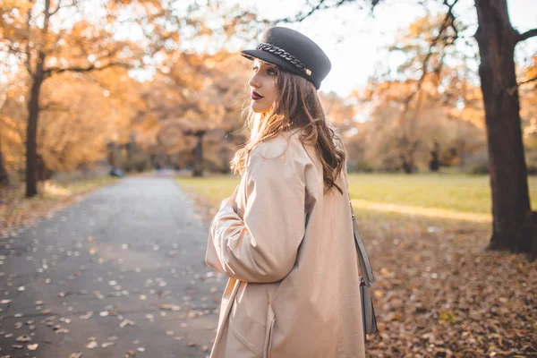 Donna piuttosto elegante con trucco di moda nel parco autunnale indossa cappello e cappotto — Foto Stock